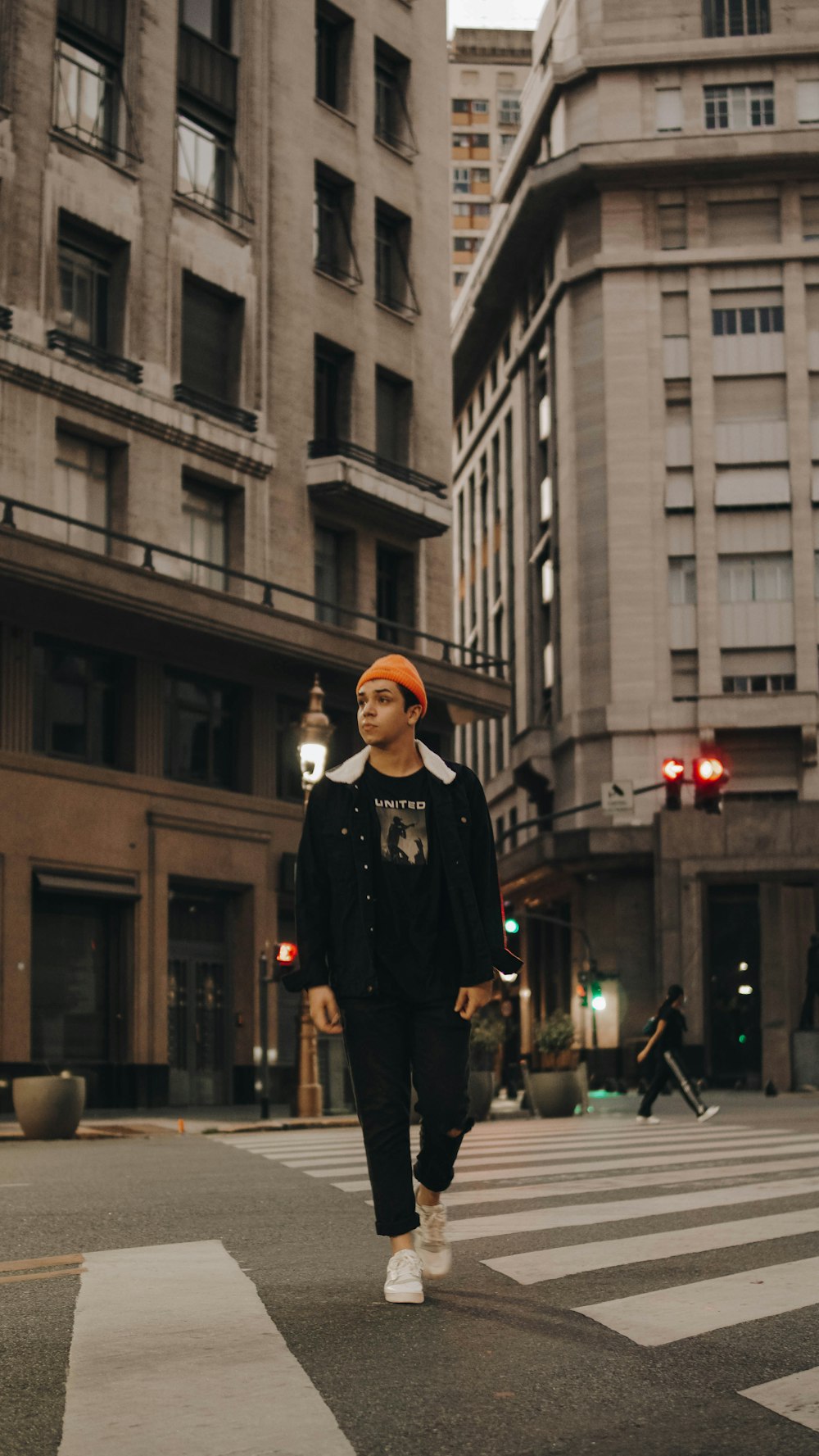 a man walking across a street next to tall buildings