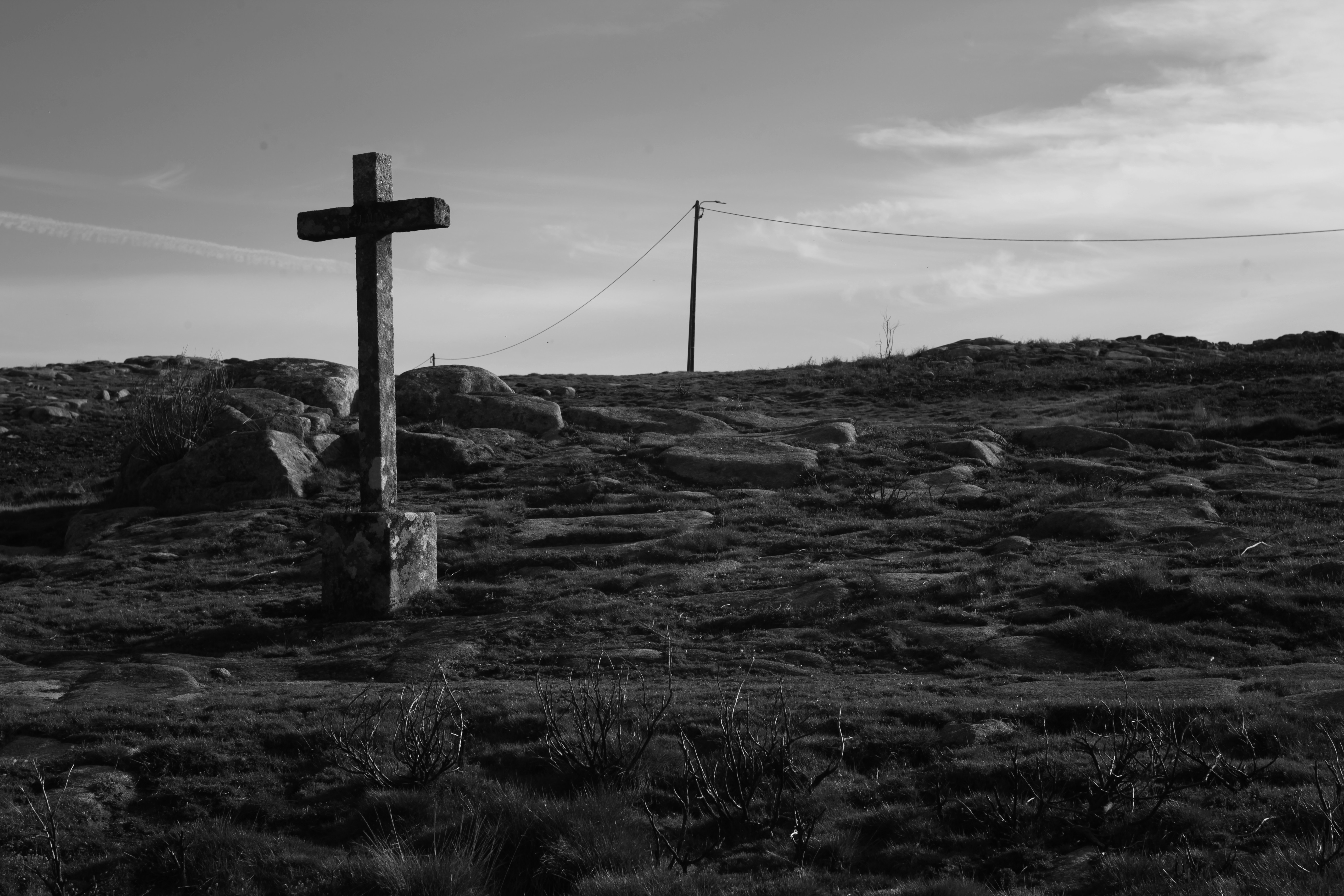 a black and white photo of a cross on a hill
