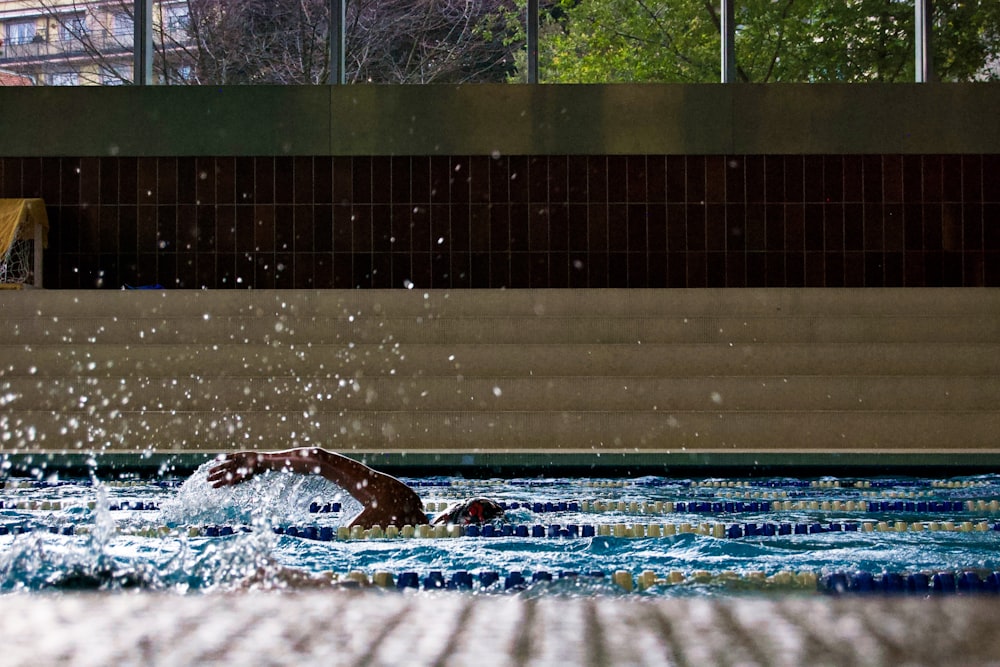 a man swimming in a swimming pool with trees in the background