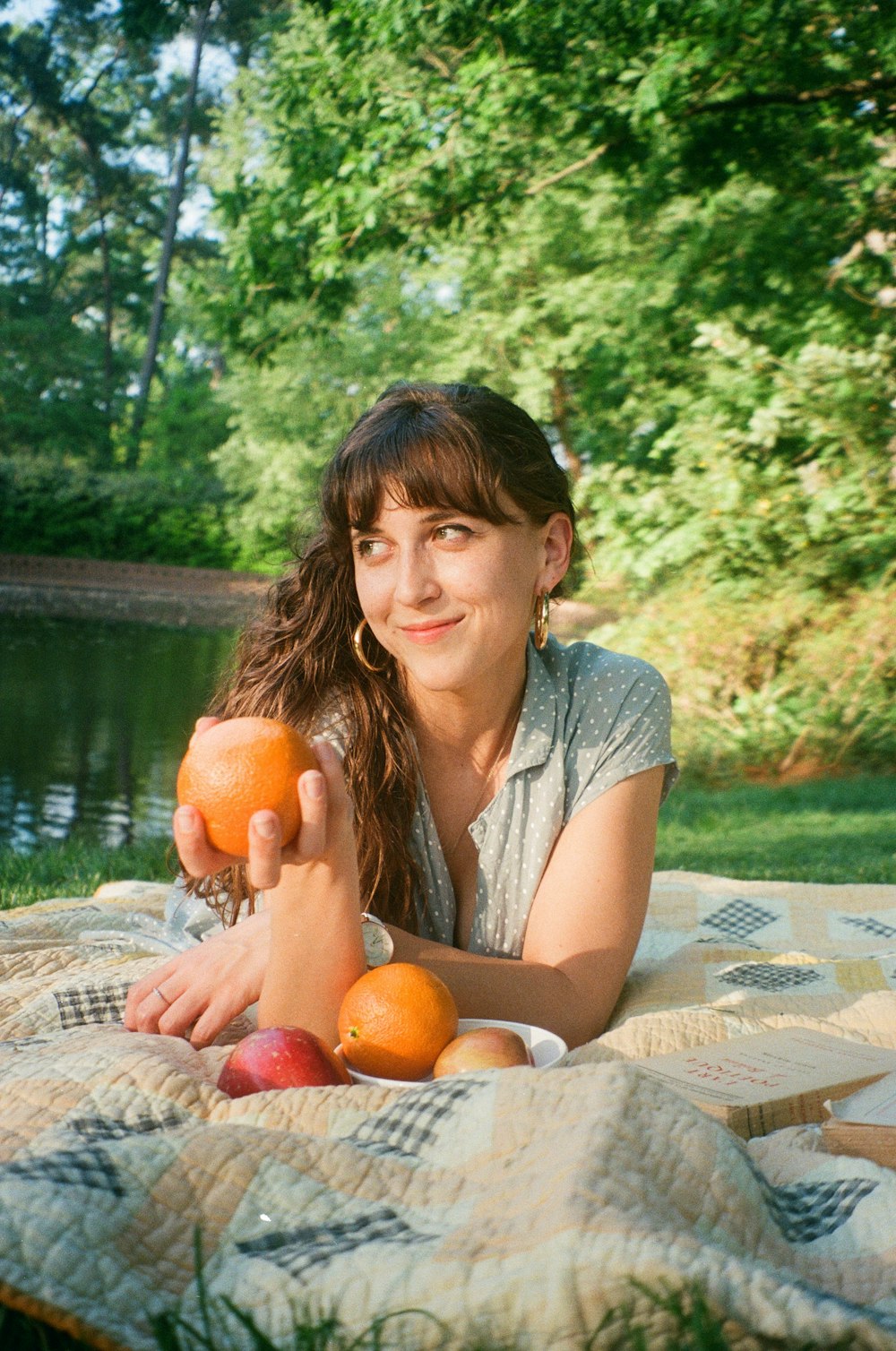 a woman laying on a blanket holding two oranges