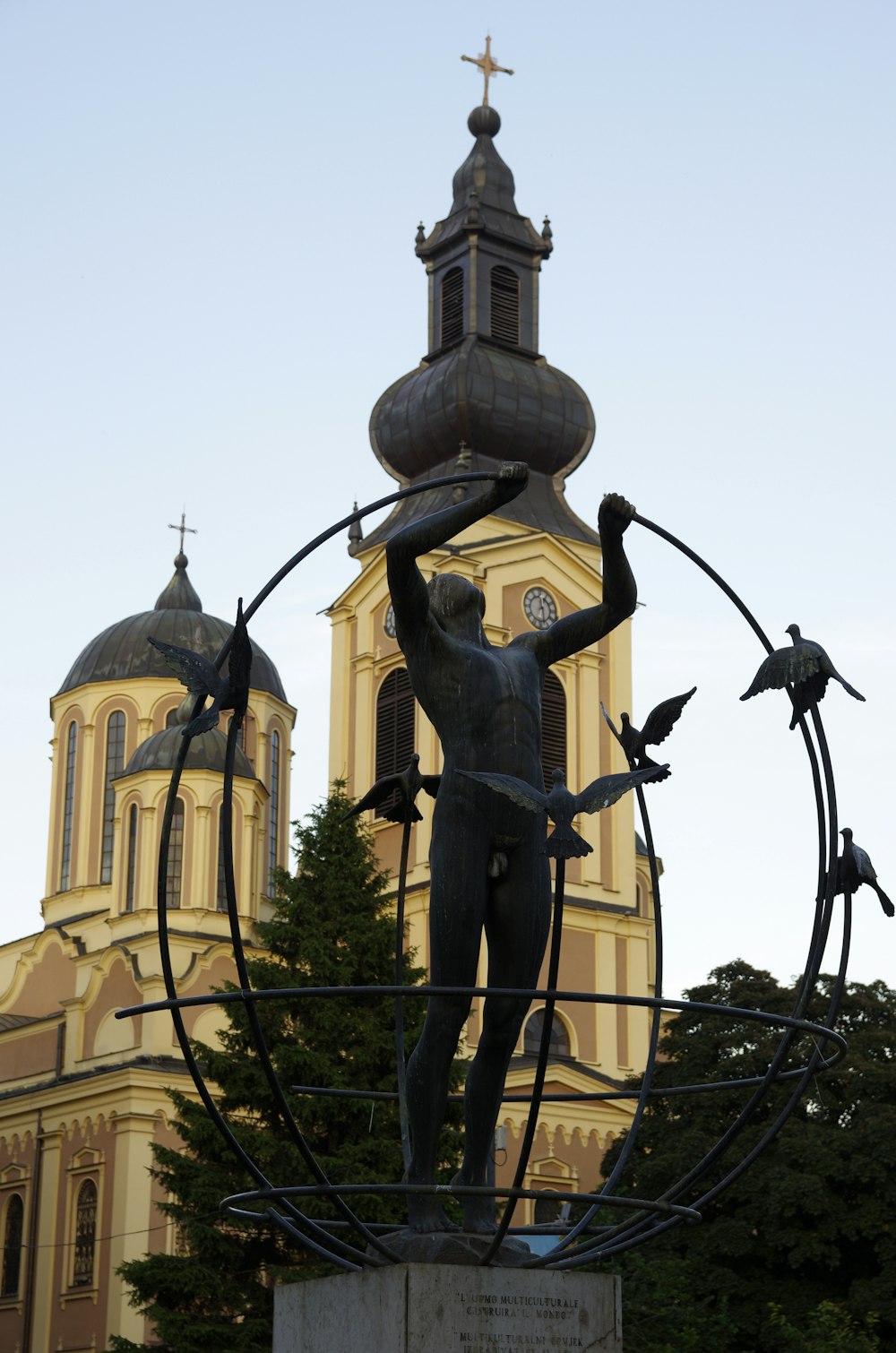 a statue of a man holding a cross in front of a church