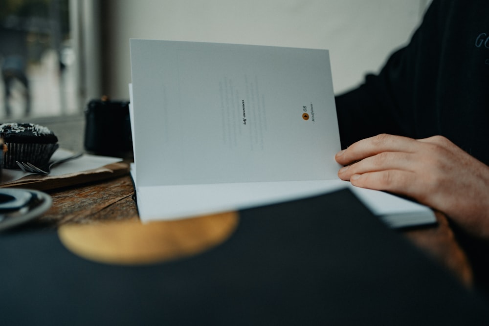 a person sitting at a table holding a piece of paper