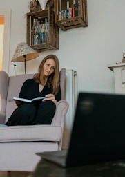 a woman sitting in a chair reading a book