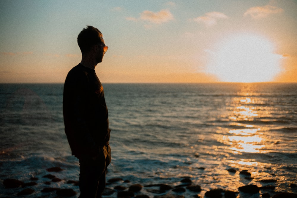 a man standing on top of a beach next to the ocean