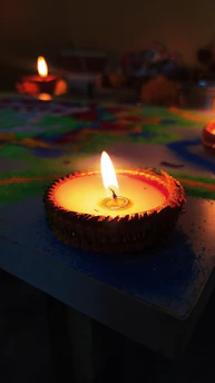 A serene close-up of a softly glowing diya floating gently against a deep red temple backdrop.