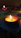 Close-up of a glowing brass diya casting warm light on a wooden altar.