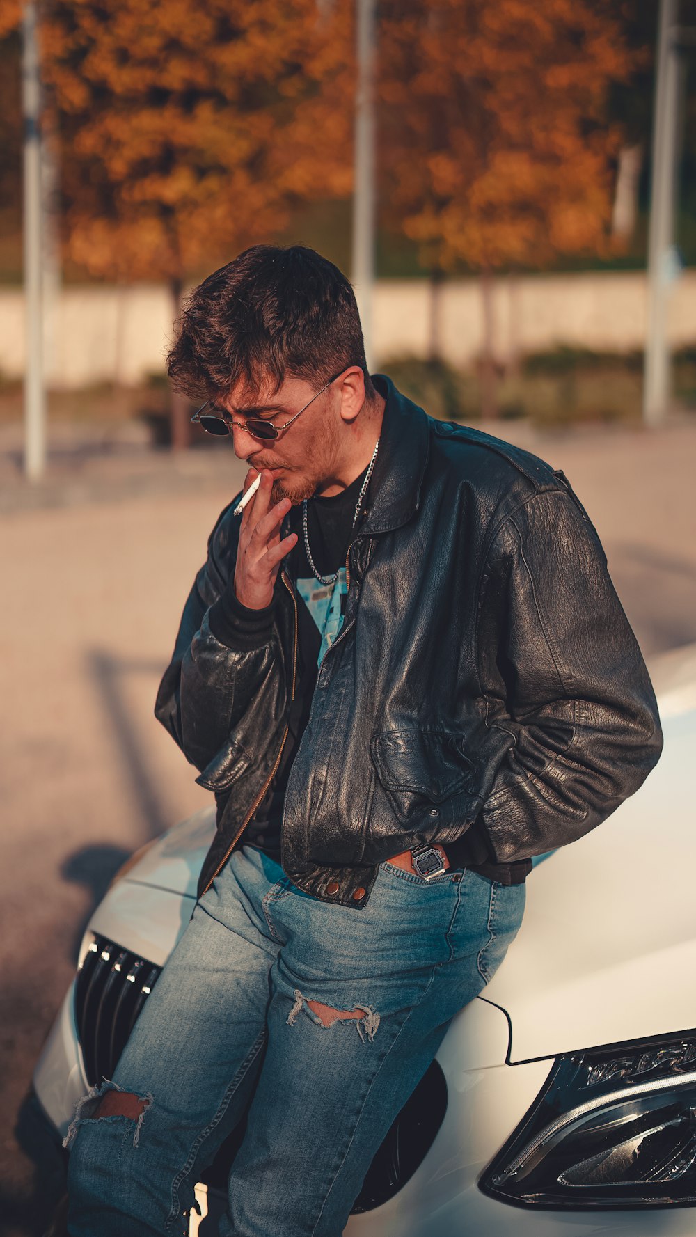 a man sitting on a car smoking a cigarette