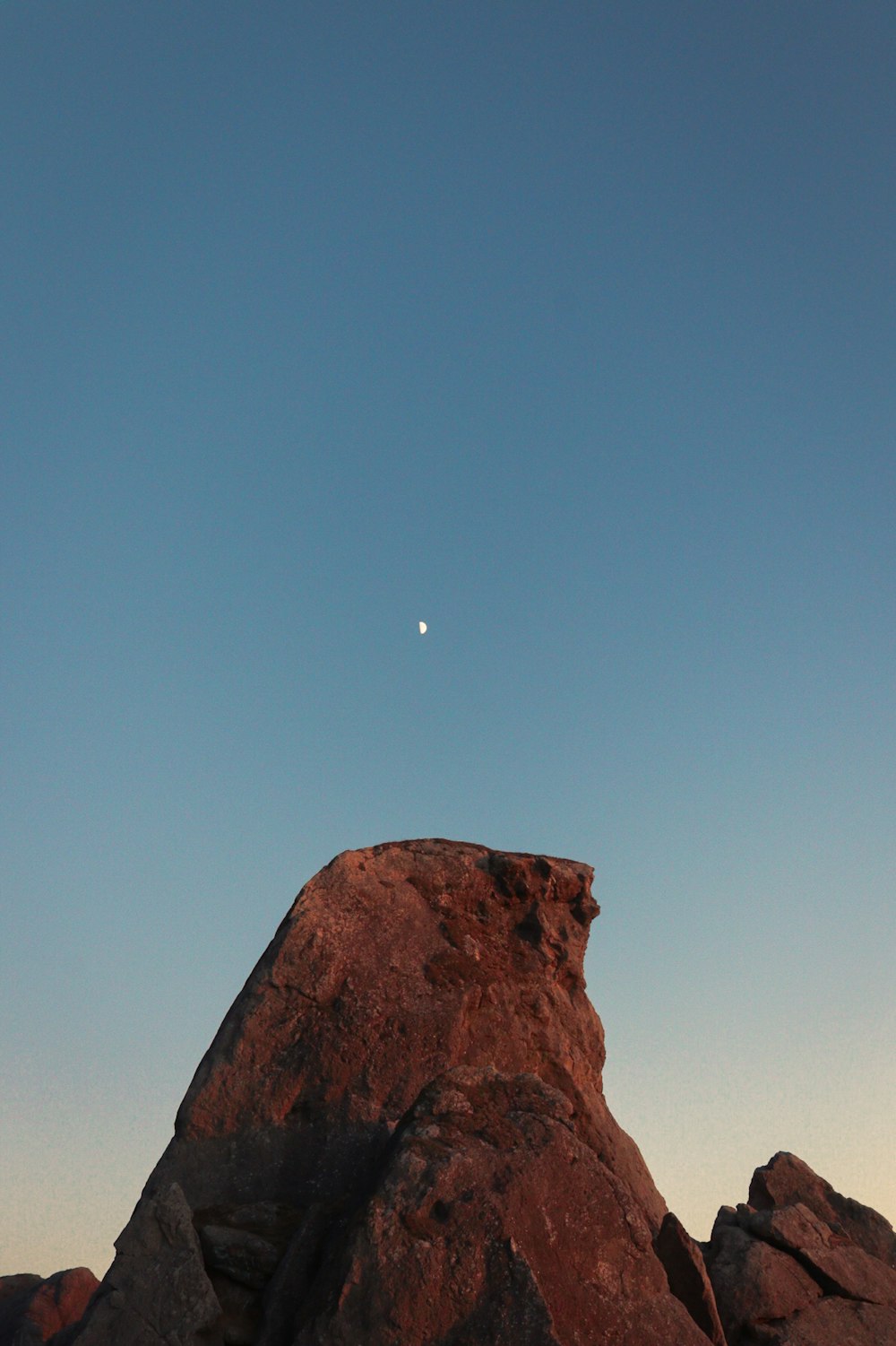 a rock formation with a moon in the sky