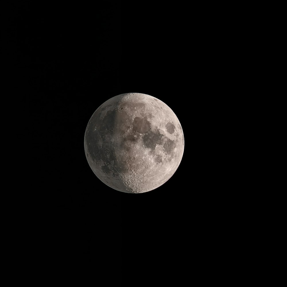 a full moon is seen in the dark sky