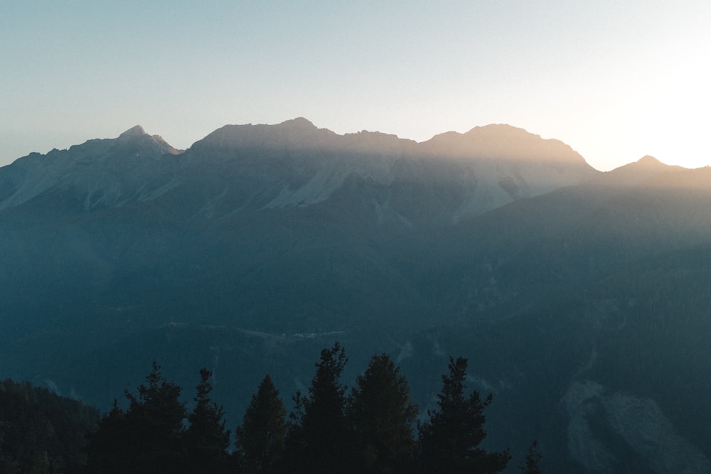 a view of a mountain range with trees in the foreground