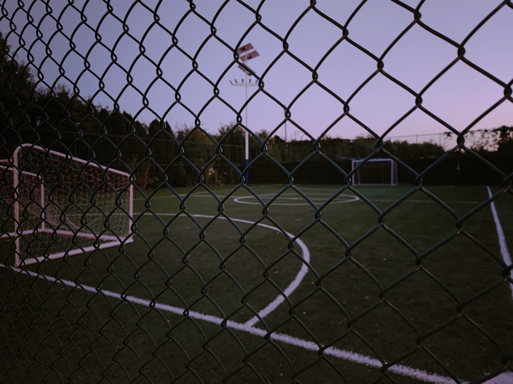 a basketball hoop is seen through a chain link fence