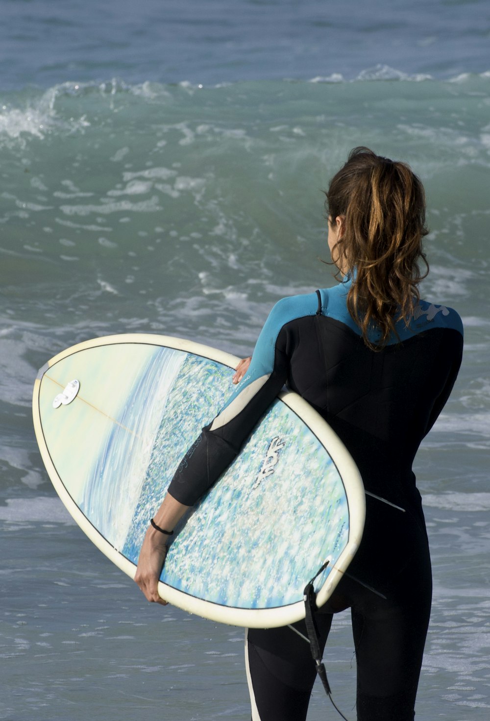 a woman in a wet suit carrying a surfboard