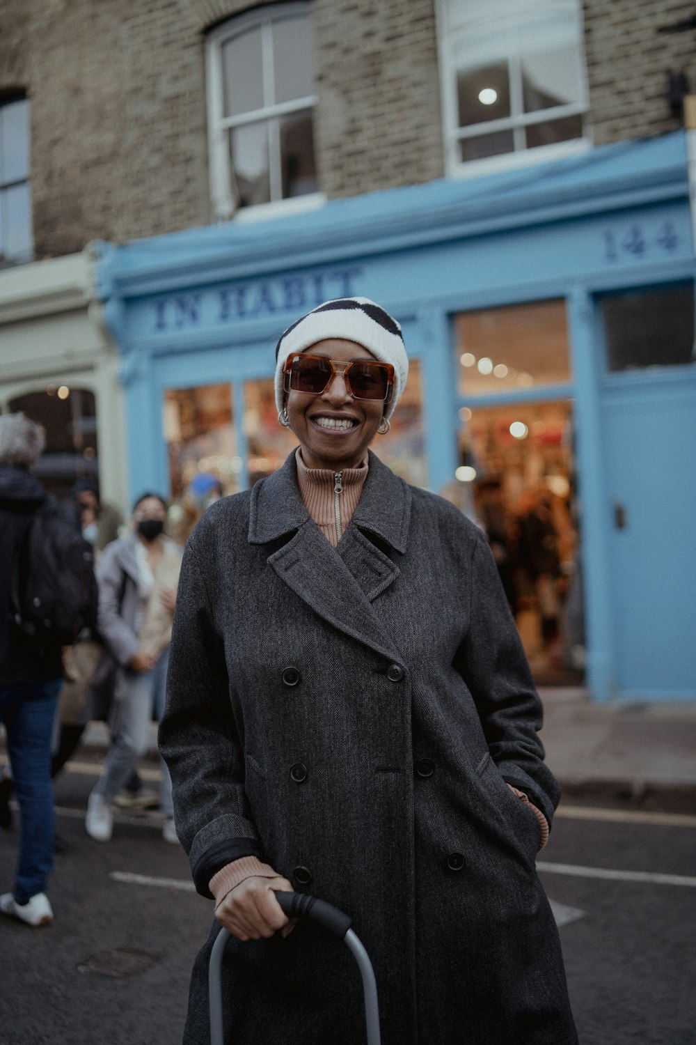 a woman in a hat and coat holding a suitcase