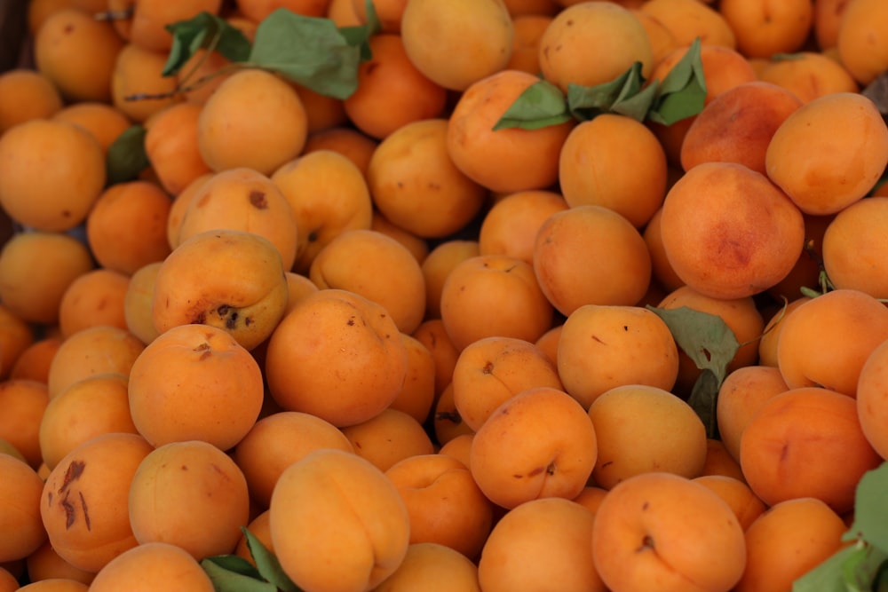 a pile of apricots with leaves on them
