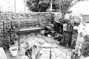 A beautifully installed stone patio with warm beige tones and forest green plants surrounding it
