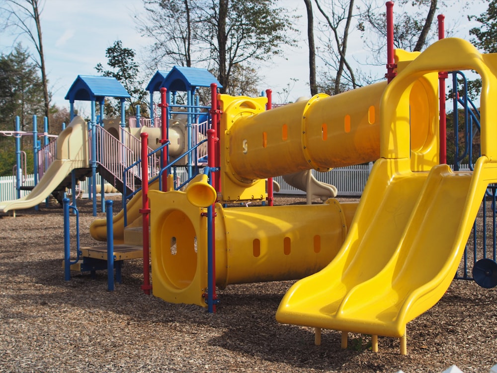 um playground com um escorregador amarelo e um escorregador azul e vermelho
