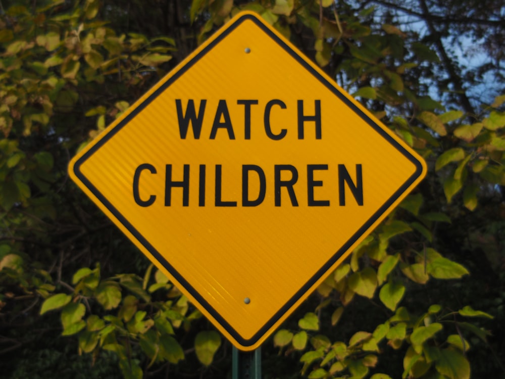 Un cartello giallo che dice Guarda i bambini su di esso