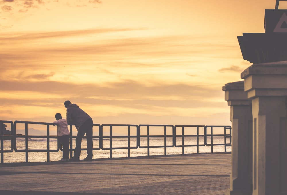 a man and a little girl standing on a pier