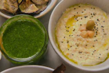 A jar of creamy tahini surrounded by sesame seeds and a drizzle of olive oil.