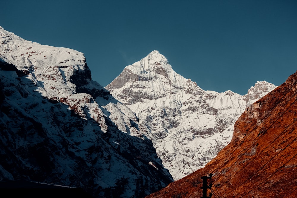 a snow covered mountain range with a cross in the foreground