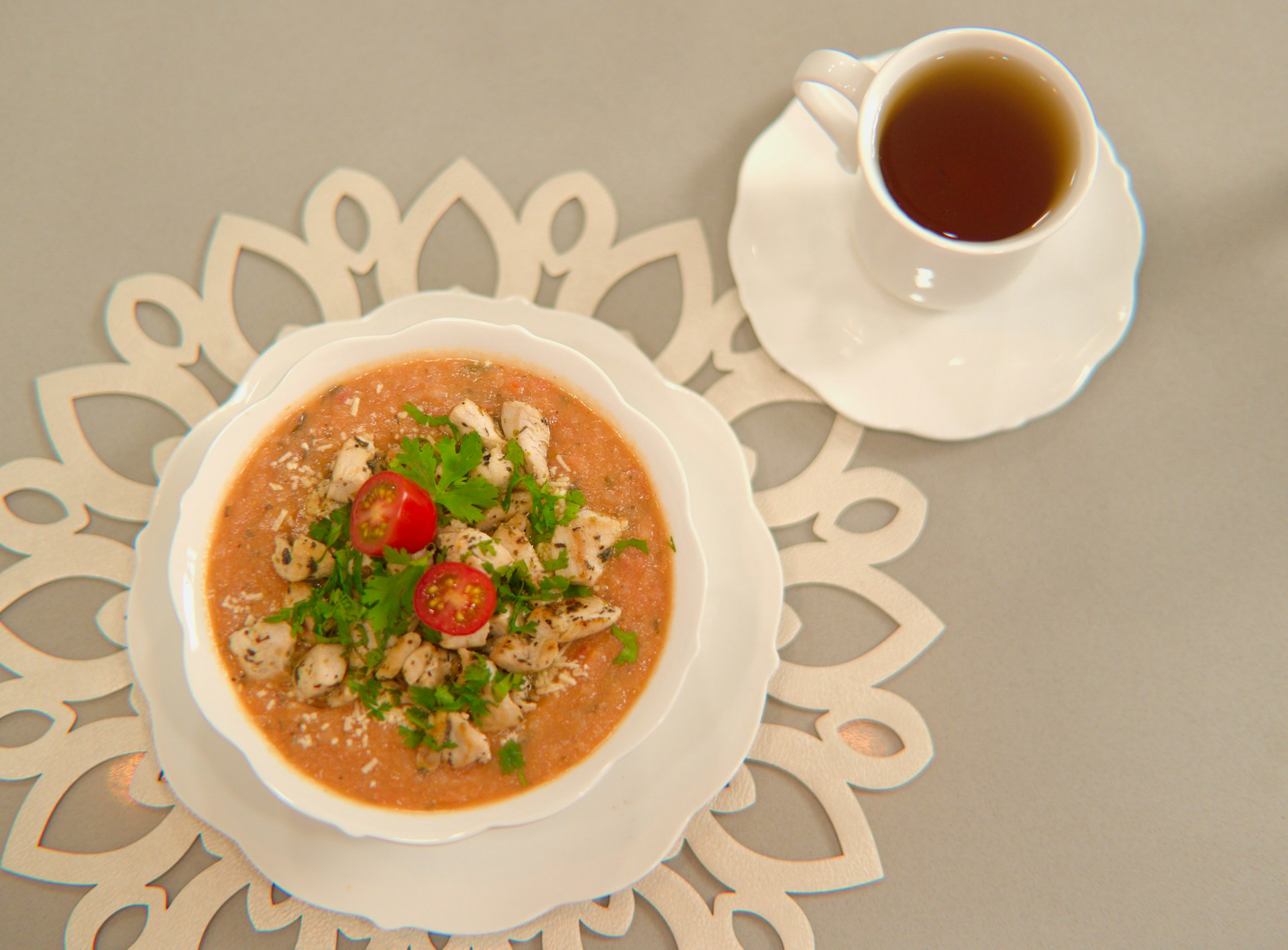 a bowl of soup on a plate next to a cup of tea