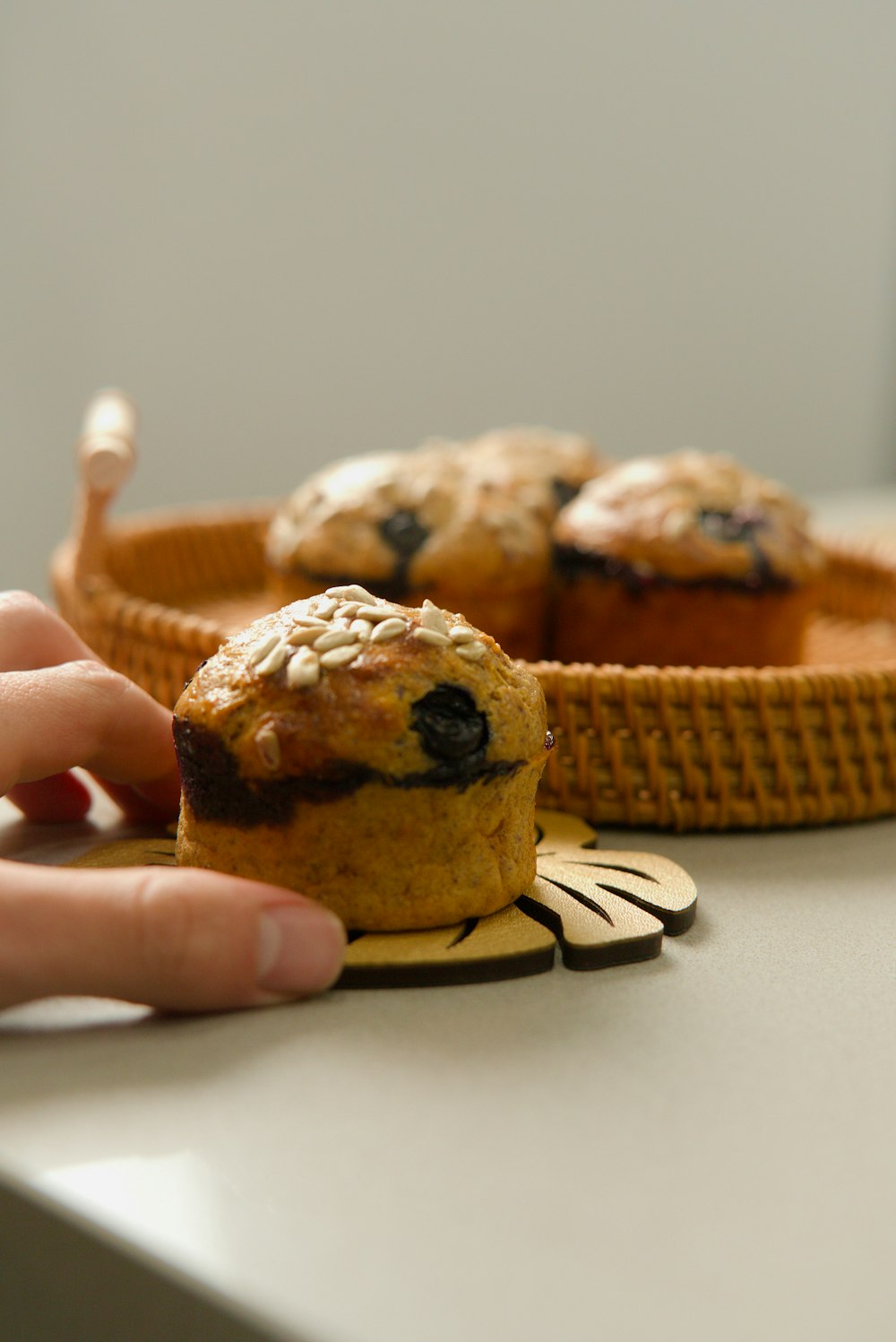 a person holding a muffin in front of a basket of muffins