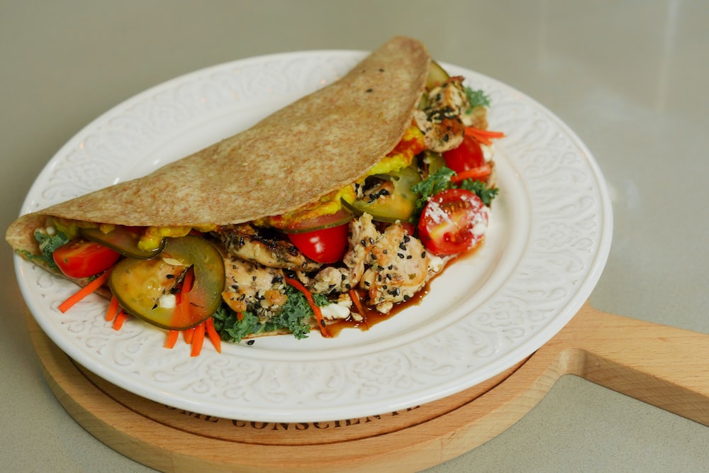 a white plate topped with a pita filled with vegetables