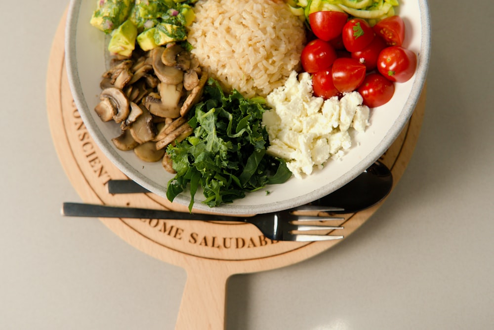 a plate of food with rice, mushrooms, tomatoes, and other vegetables