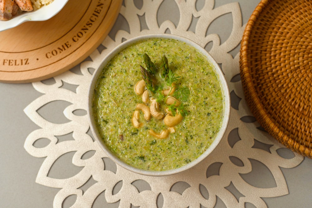 un bol de soupe au brocoli à côté d’une assiette de croissants