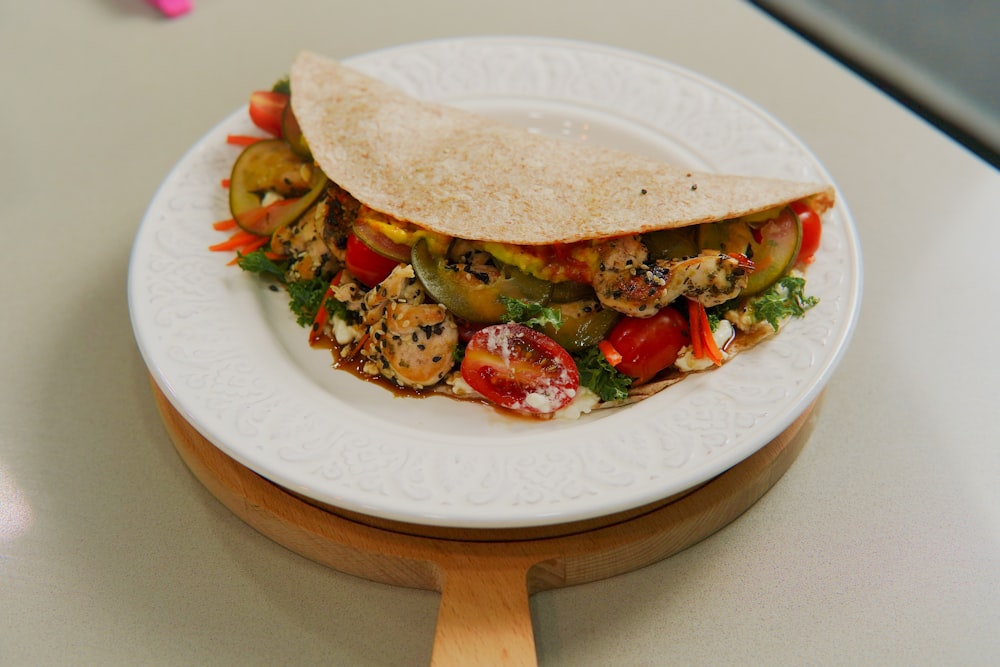 a white plate topped with a taco and vegetables