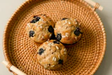 Freshly baked muffins bursting with blueberries in a basket.