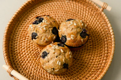 Freshly baked muffins bursting with blueberries in a basket.