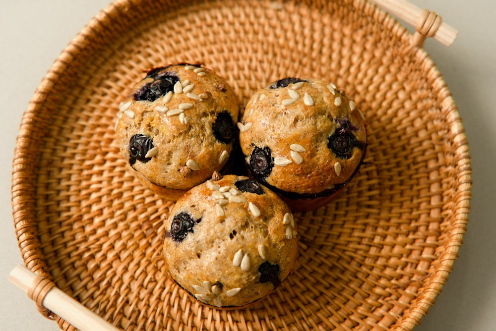 three blueberry muffins on a wicker plate