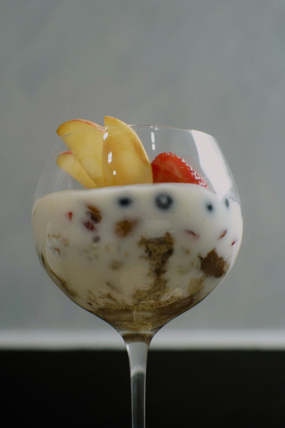 a dessert in a wine glass with fruit on top