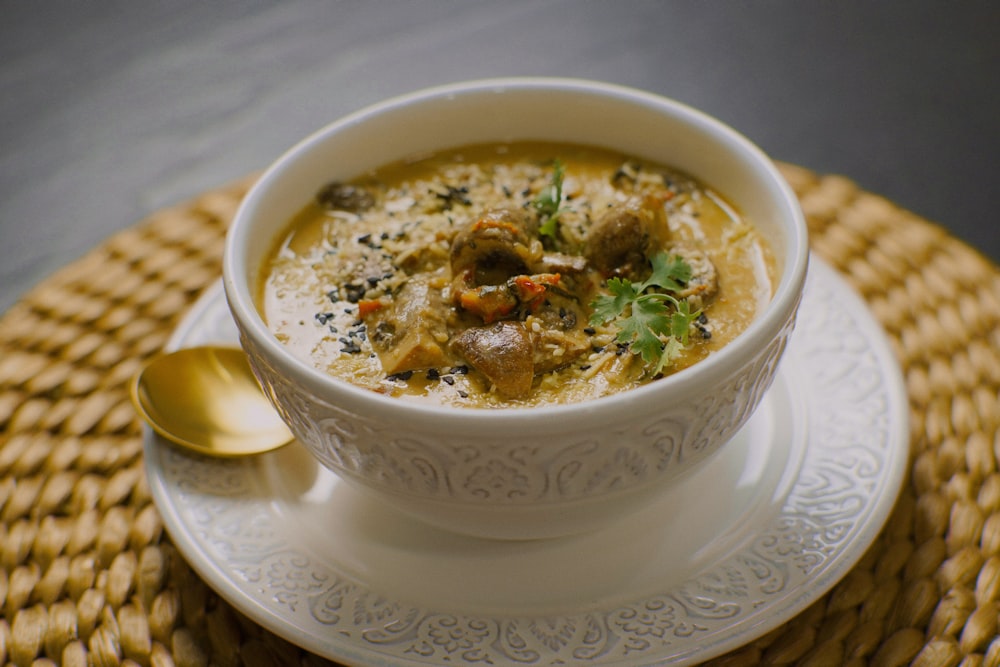 uma tigela de sopa em um prato com uma colher