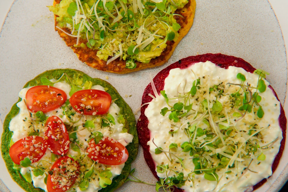 three small pizzas with toppings on a plate