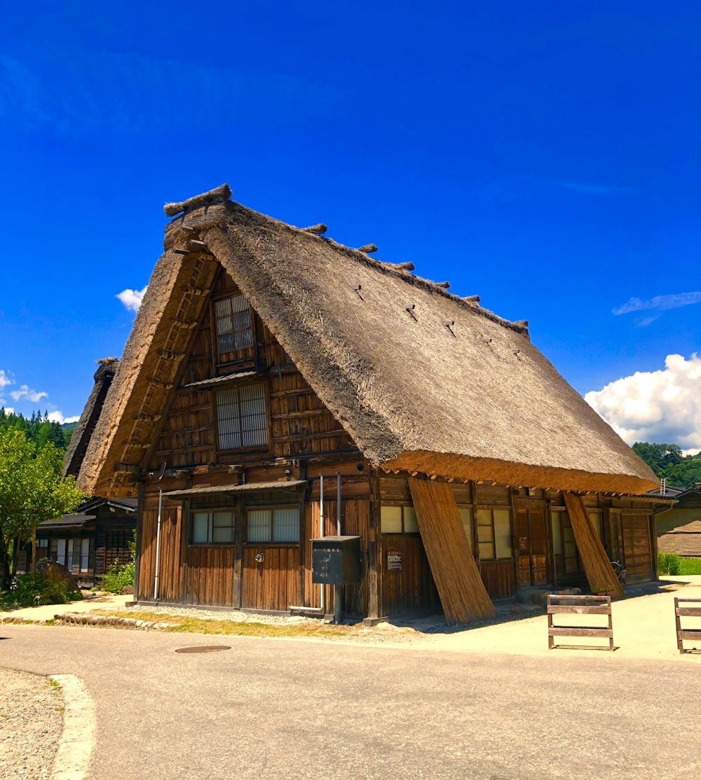 a building with a thatched roof and a bench in front of it