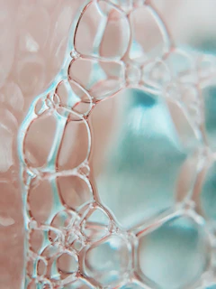 Close-up of soap bubbles sparkling in soft aqua and blue tones.