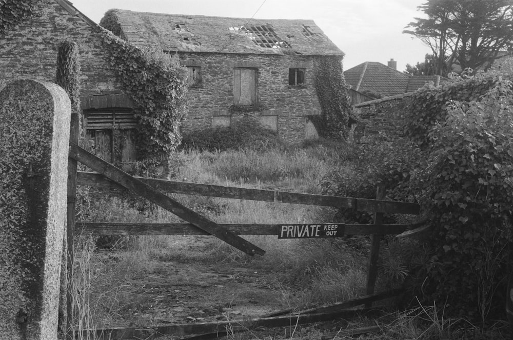 a black and white photo of a gate and a house