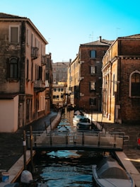 a boat is docked in a canal between two buildings
