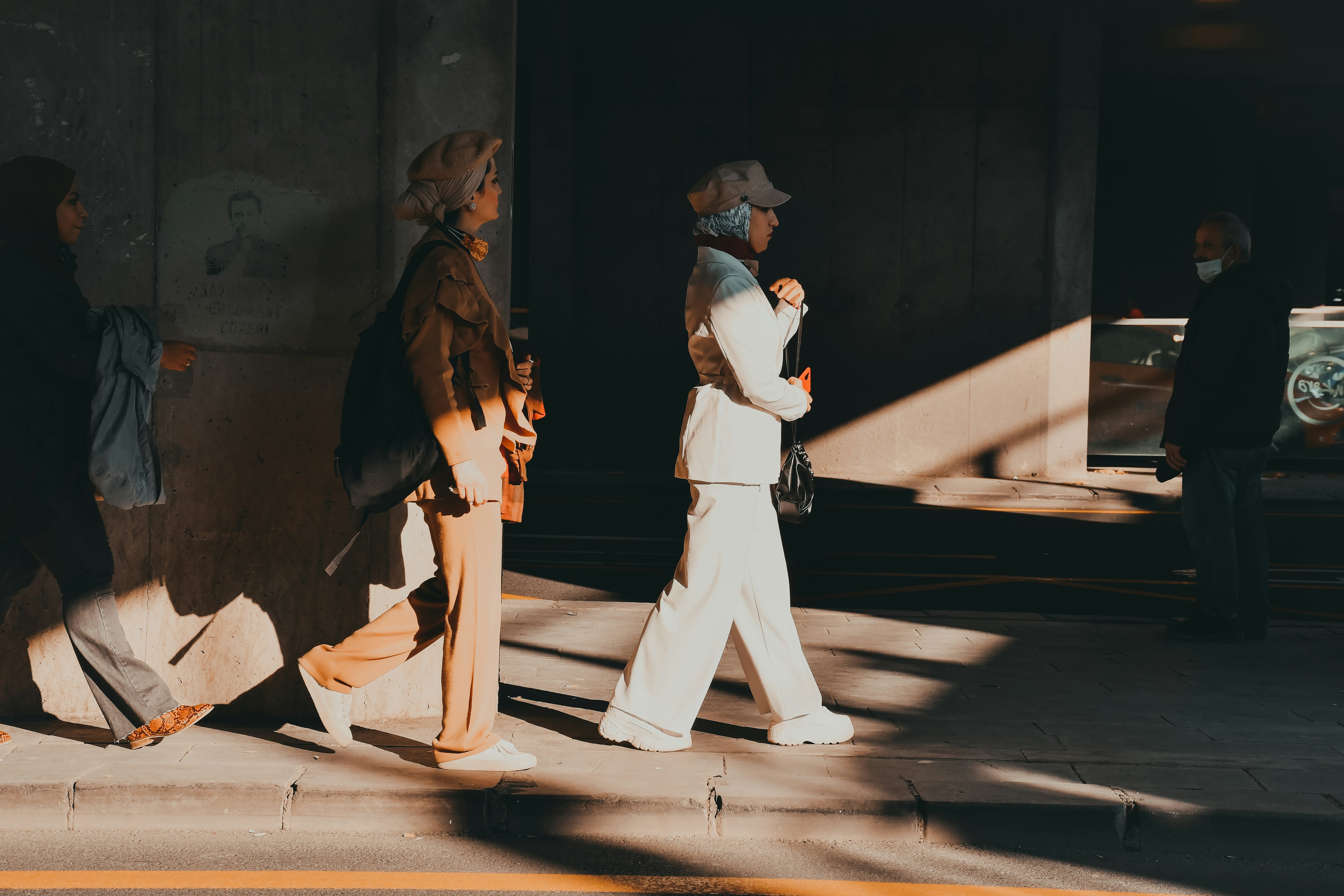 two people walking down a street next to a building