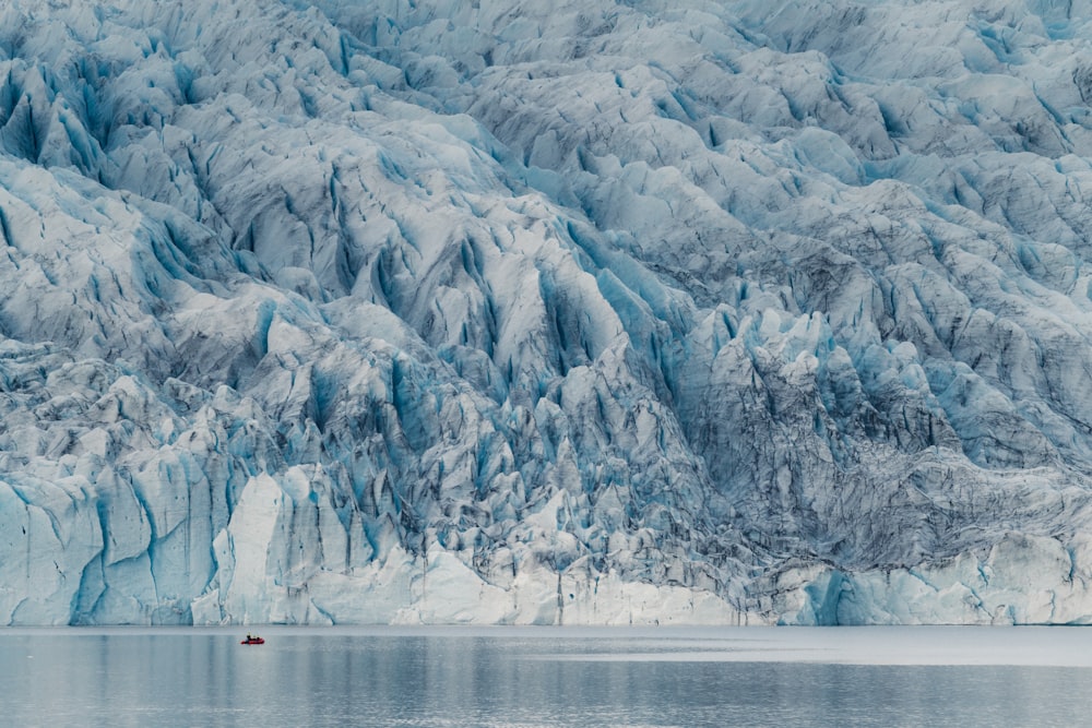 a large glacier with a boat in the water