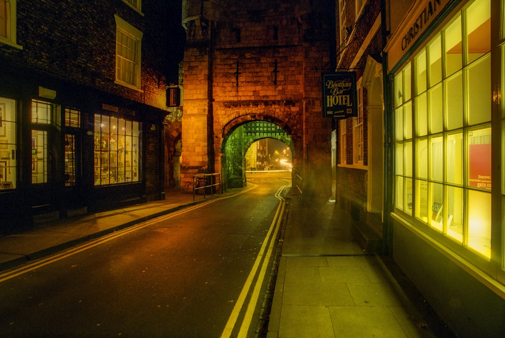 a narrow street with a stone arch at night
