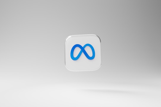 A three-dimensional square icon with a transparent background features a prominent blue infinity symbol in the center. The backdrop is a smooth gradient of light gray tones.