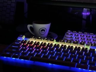 a cup of coffee sitting on top of a keyboard