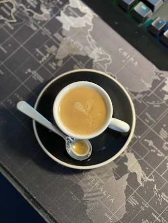 a cup of coffee sitting on top of a black plate