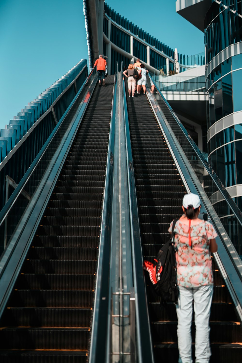 a woman is walking up an escalator on a sunny day