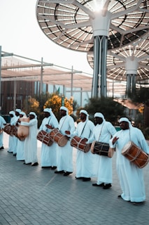 a group of men dressed in white holding drums