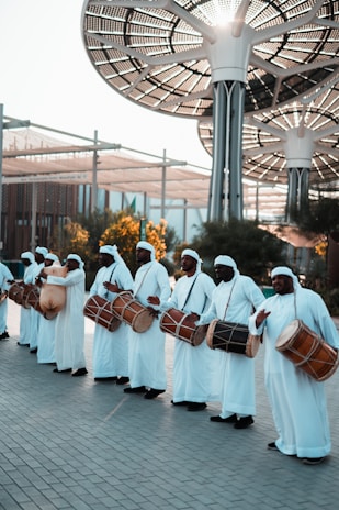 a group of men dressed in white holding drums