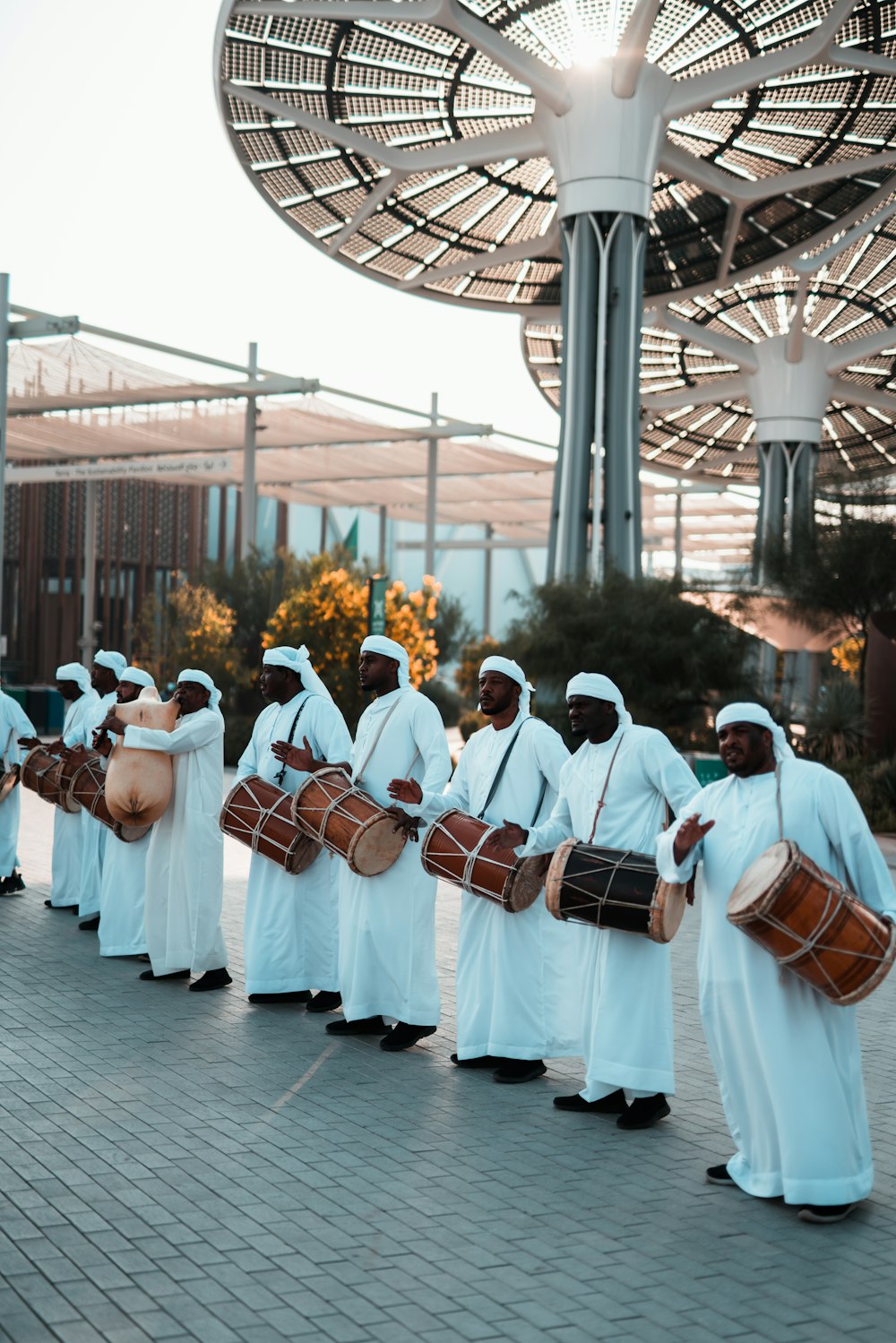 a group of men dressed in white holding drums